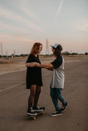 Man helping girlfriend to skate on road