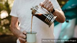 Close-up of a mature man pouring coffee in a mug at campsite 42Rg74