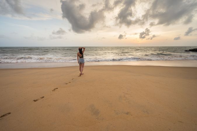 Woman in beachwear walking on sand barefoot
