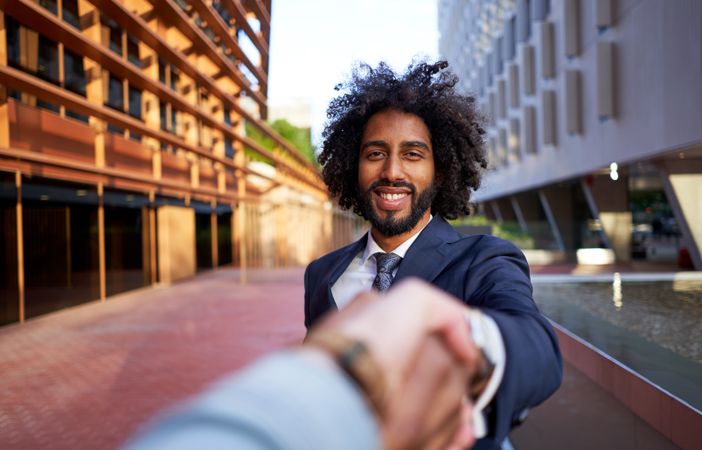 happy businessman shaking hands with partner and looking at camera