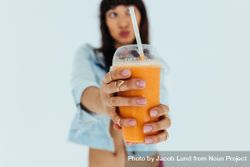 Close up of female hands holding fresh orange juice glass in front 5a7zWb