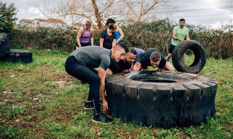 Participants in an obstacle course turning a wheel