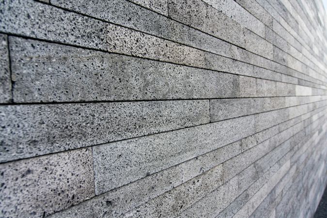 A close-up photo of a grey stone wall arranged in long horizontal lines
