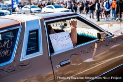 Los Angeles, CA, USA — June 7th, 2020: woman riding in car with “no justice no peace” protest sign 5ng3M4