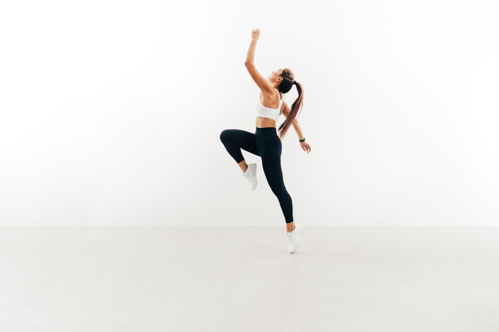 Woman working out with her knee and arm up in bright room