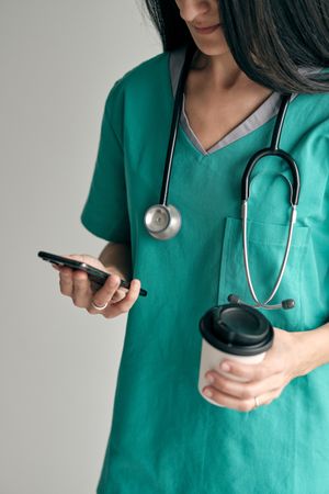 Crop doctor with takeaway coffee chatting on smartphone