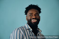 Closeup portrait of a smiling Black man in blue studio shoot looking away from the camera 5okR85