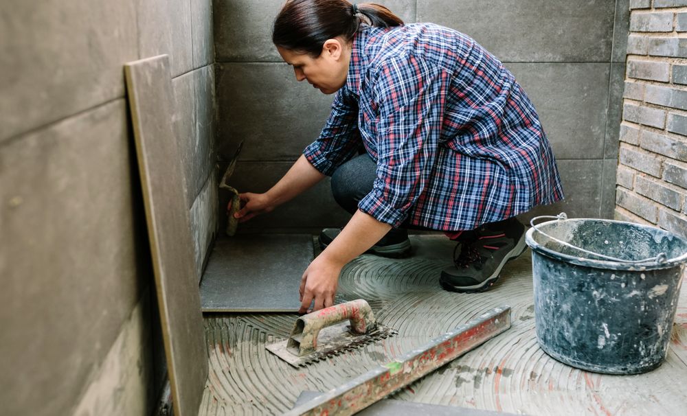 Female manual worker laying a new tile floor