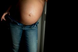 Crop pregnant woman near open door
