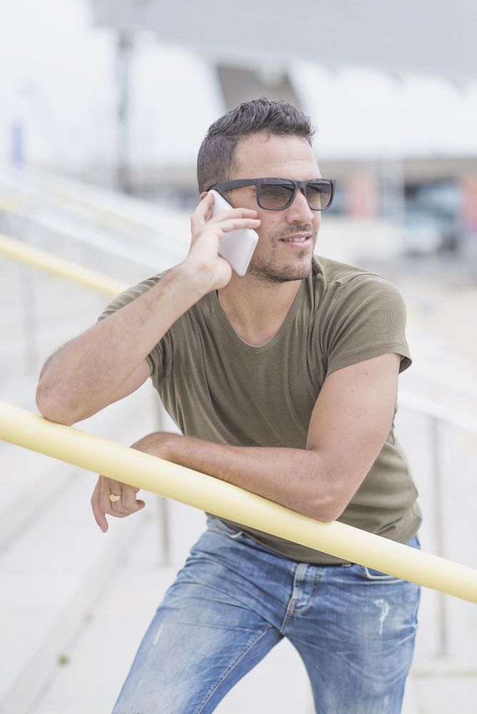 Male standing on outdoor staircase talking on cellphone