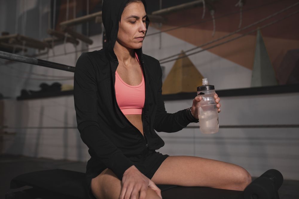Smiling woman with bottle of water in gym