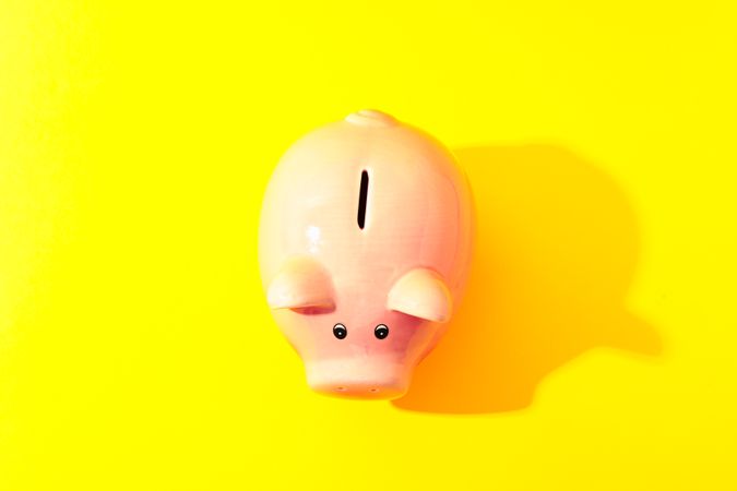 Happy piggy bank on yellow background, space for text and top view. Finance, saving money