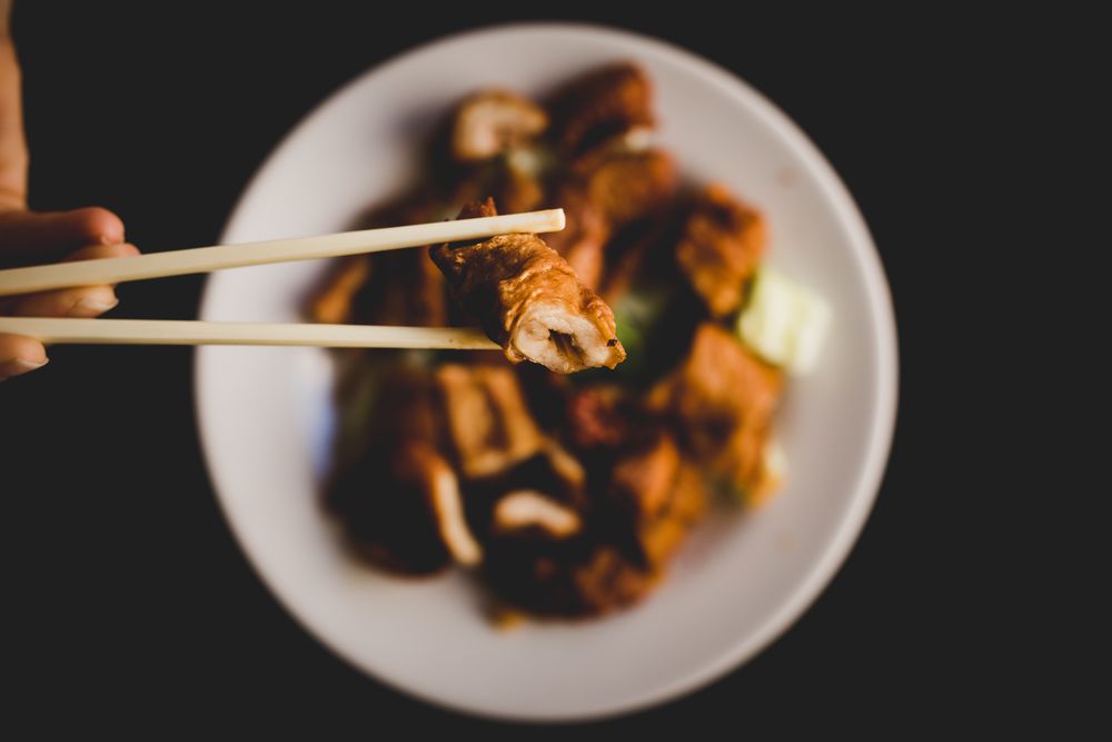 Hand eating prepared delicious pork belly with vegetables