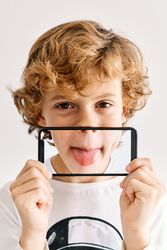 Child posing with his mobile phone and photos made of parts of his face