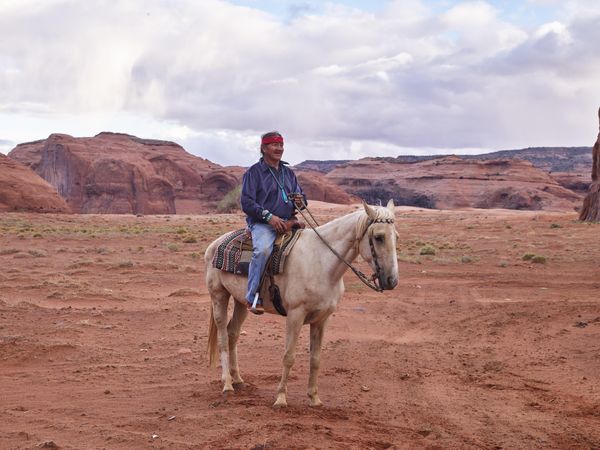 Mature Native American man riding a horse in sand desert