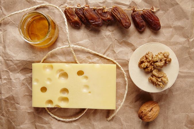 Top view of cheese, honey, dates and walnuts on paper