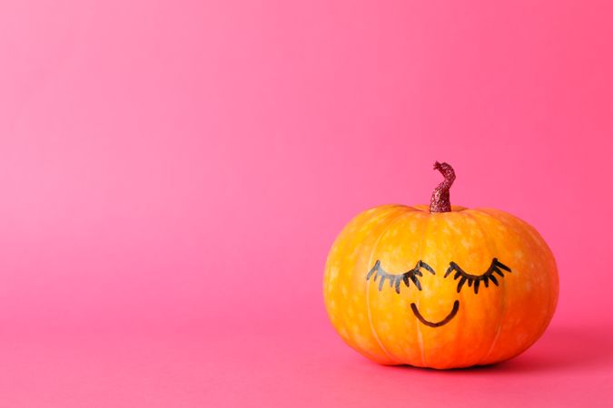 Pumpkin with smile on pink background, space for text