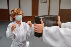 Boy in mask doing karate in dojo