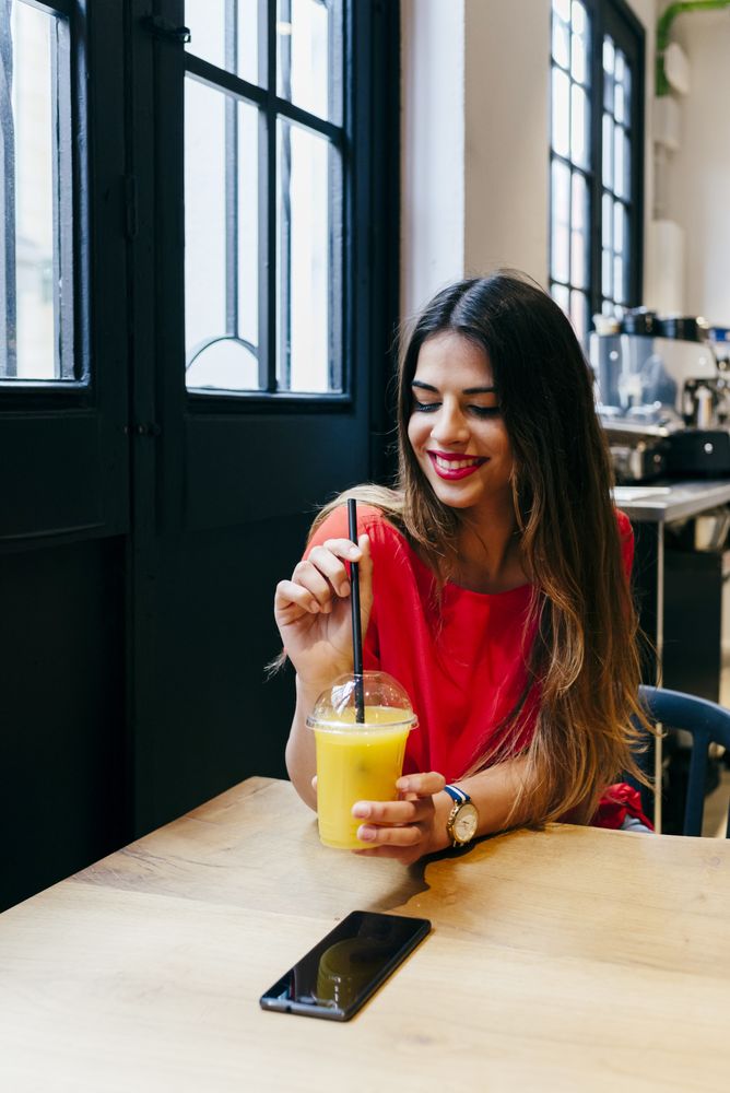 Smiling woman sipping smoothie in cafe