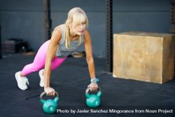 Fit woman doing plank workout with kettle bells 49m1Pn