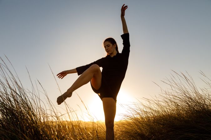 Woman posing between field at sunset