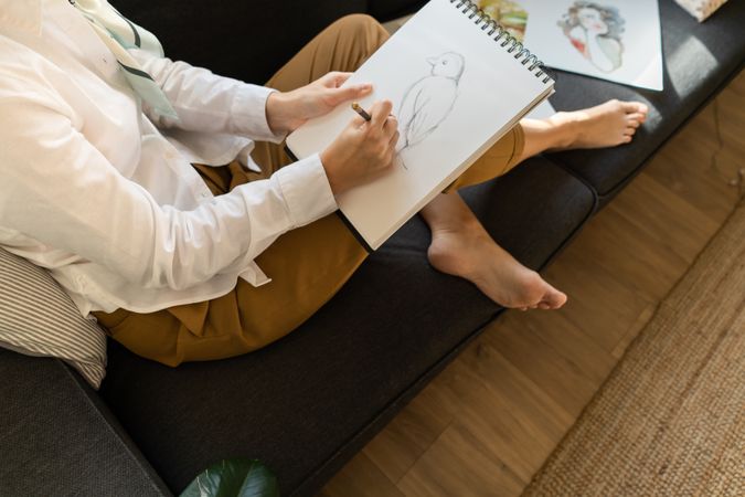 Woman writing on paper on sofa in room