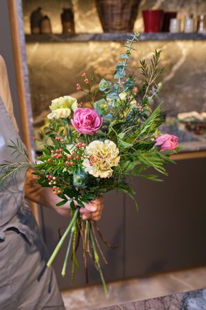 Crop female florist in with flower bouquet