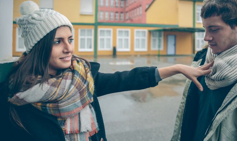 Woman pushing man away playfully dressed in winter clothes outside