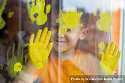 Boy printing window glass with yellow paint 4NrZe4