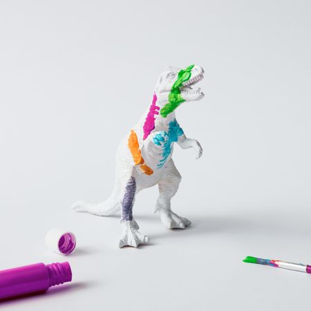 Plastic dinosaur splattered with different colors of paint