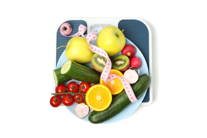 Scales, measuring tape and vegetarian food isolated on blank background