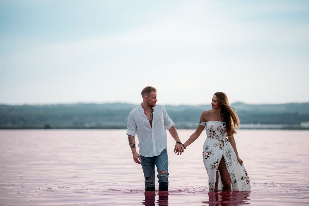 adorable couple walking into an amazing beach with pink water