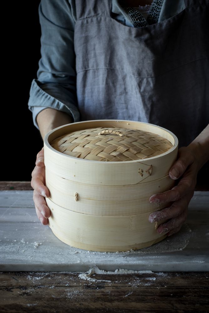 Person holding a bamboo steamer