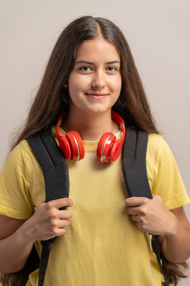 Portrait of a smiling young student holding her backpack, ready for back to school.