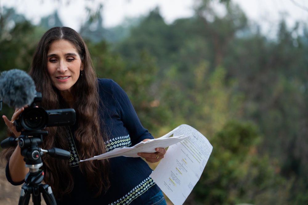 Woman holding script and looking through viewfinder while filming outside