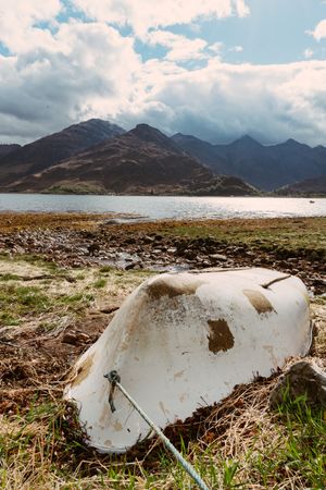 Aged boat on shore of lake in mountains