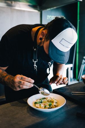 Tattooed chef head down plating sea food fish