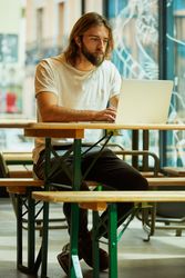 man sitting at table and typing on laptop
