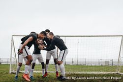 Soccer players joining hands standing in a huddle having a pep talk bx3wd4