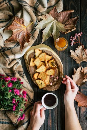 Crop hands with tea smearing honey on croutons
