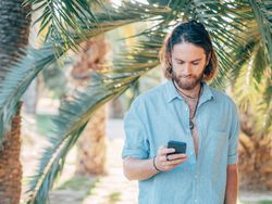 Young hipster man texting in jungle