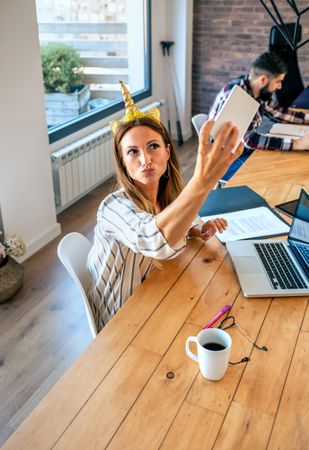 Business woman taking selfie with unicorn headband
