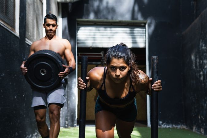 Hispanic woman pushing sled near instructor