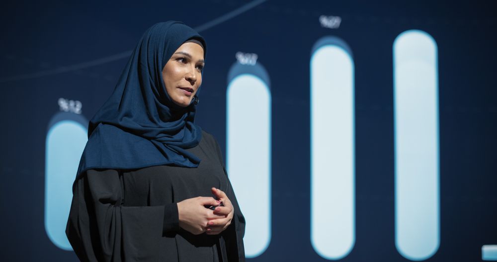 Successful Middle Eastern Female Speaker Presenting a New Product, Showing Infographics, Statistics Animation on Big Screen.
