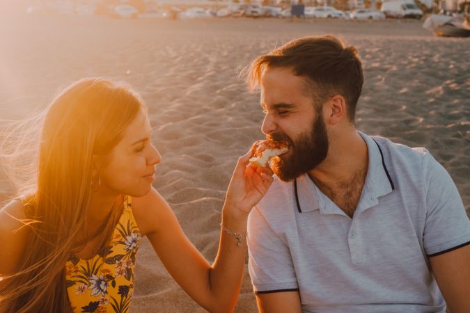 Lovely couple eating together at sandy beach