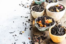 Tea leaves in bowls on marble background with copy space
