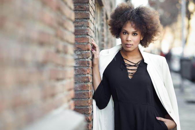 Female in dress with blazer standing next to outdoor wall