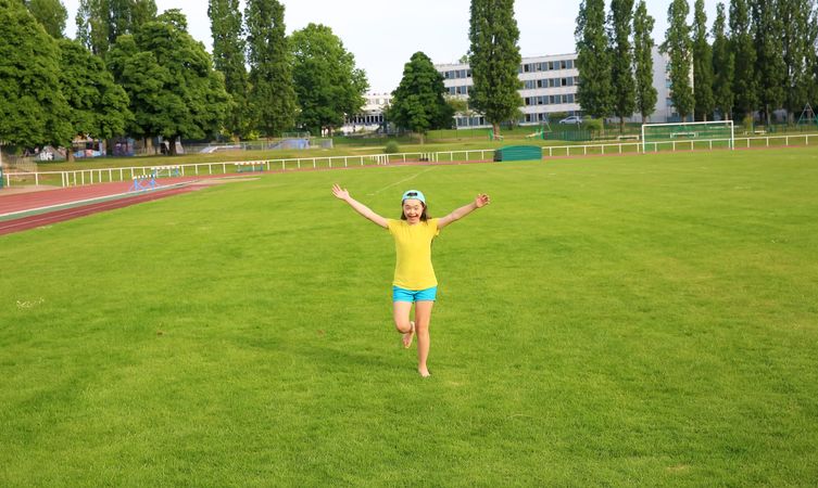 Joyful young girl playing in an open grass field