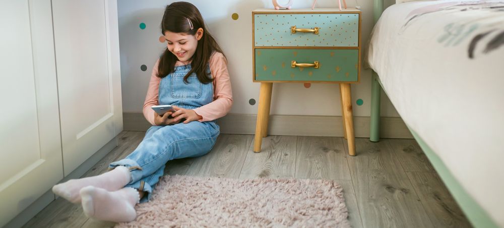 Girl laughing looking at the mobile sitting on the floor