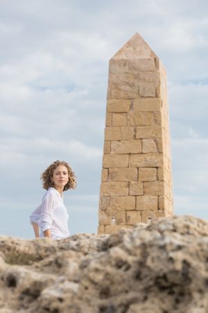 Young woman near brick monument and blue sky